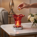 Person pouring fragrance oil into Red Ember warmer glowing with warm electric light on marble side table